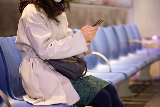 バス停で携帯電話を触る女性
